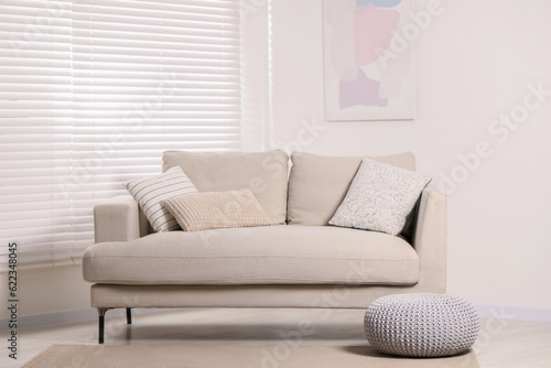 Stylish soft sofa with cushions in living room. Interior design