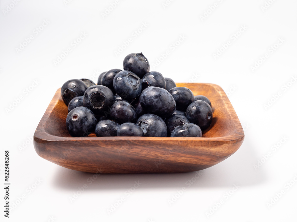 Ripe blueberries in a wooden bowl on a light background. blueberries close up Ripe blueberries in a wooden bowl on a light background. blueberries close up
