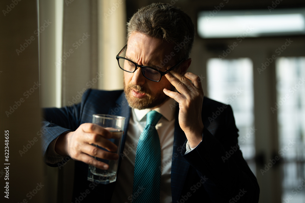 Sad man with laptop got migraine touches her head because of pain. Man manager with strong headache. Overworked freelancer or manager at office. Man taking a Medicine pill from headache migraine. Sad man with laptop got migraine touches her head because of pain. Man manager with strong headache. Overworked freelancer or manager at office. Man taking a Medicine pill from headache migraine.