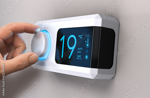 Hand turning a home thermostat knob to set temperature on energy saving mode. Celsius units. Composite image between a photography and a 3D background. photo