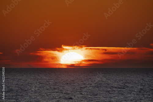 Photo of a seascape, sunset, the sun goes beyond the horizon, close-up photo.