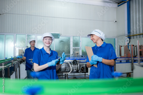 Young woman factory workers in blue uniforms and hats working together in drinking water factory