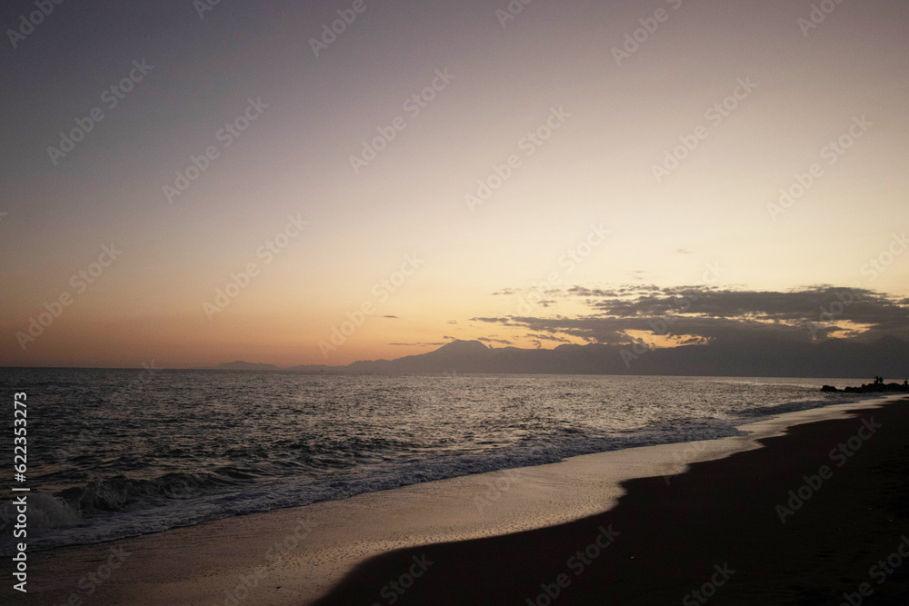 Obraz premium Beautiful view of the sea, waves and mountains at sunset. The horizon above the water.