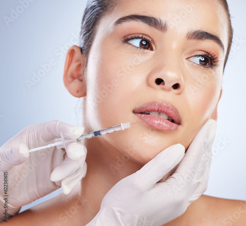 Syringe, woman and plastic surgery with skincare, collagen and beauty against a studio background. Female person, girl or model with a needle, cosmetics or body transformation with aesthetic and care