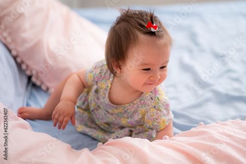 lifestyle home portrait of happy and adorable 9 months old mixed ethnicity Asian Caucasian baby girl playing cheerful and carefree on bed looking sweet and cute in childhood concept