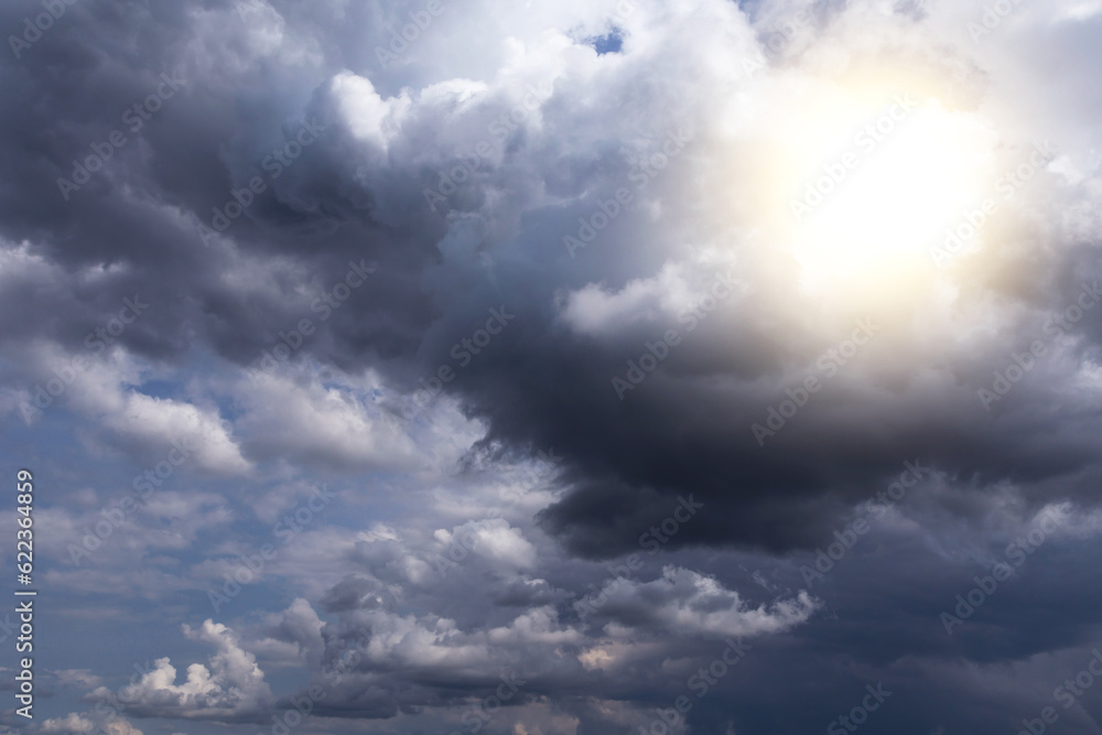 Epic dramatic storm dark grey sky and clouds with yellow white sun and sunlight, thunderstorm