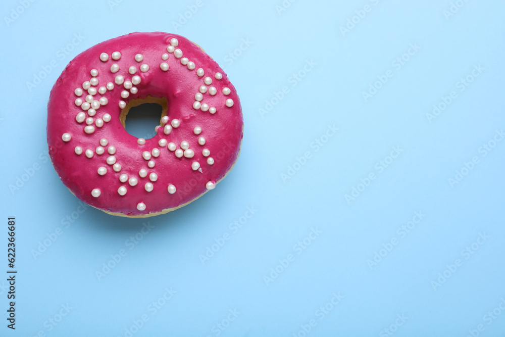 Tasty glazed donut decorated with sprinkles on light blue background, top view. Space for text Tasty glazed donut decorated with sprinkles on light blue background, top view. Space for text