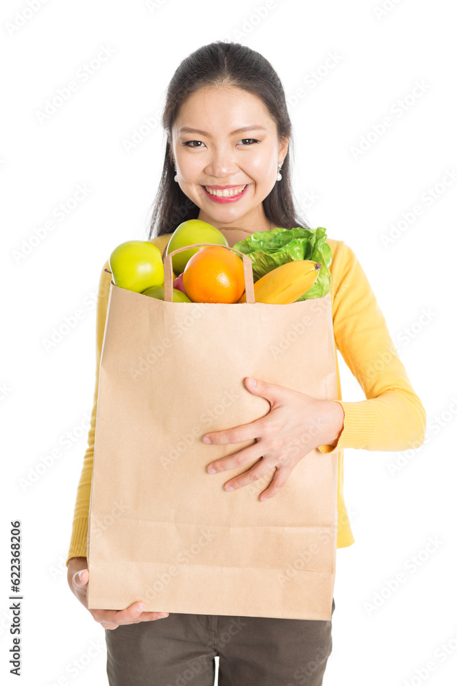 Happy young Asian woman shopper, hands holding shopping bags filled with groceries and smiling, isolated standing on white background. Happy young Asian woman shopper, hands holding shopping bags filled with groceries and smiling, isolated standing on white background.