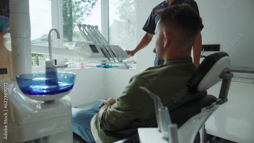 Man sits in a dental chair. Dentist hold a dental instrument starting treats teeth. Hydience and health. Modern clinic Man sits in a dental chair. Dentist hold a dental instrument starting treats teeth. Hydience and health. Modern clinic