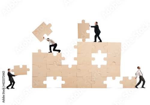 Team of businessmen collaborate and cooperate to build a puzzle