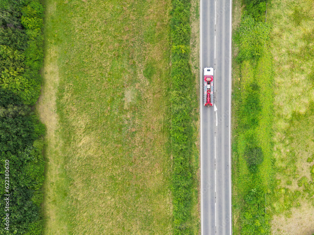 Drone top down view of a commercial truck seen travelling on a single lane bypass road in
