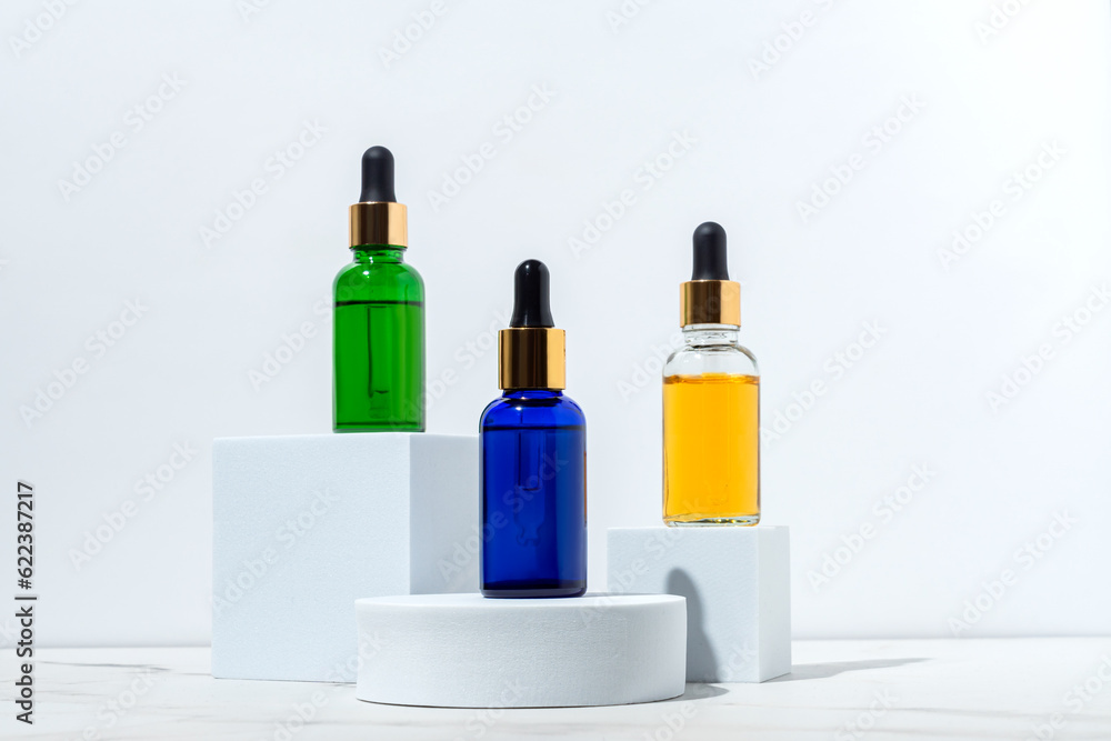 Face serum dropp bottles on white podiums on white background. Home routine skin care cosmetic set. Unbranded bottles for your design. Face serum dropp bottles on white podiums on white background. Home routine skin care cosmetic set. Unbranded bottles for your design.