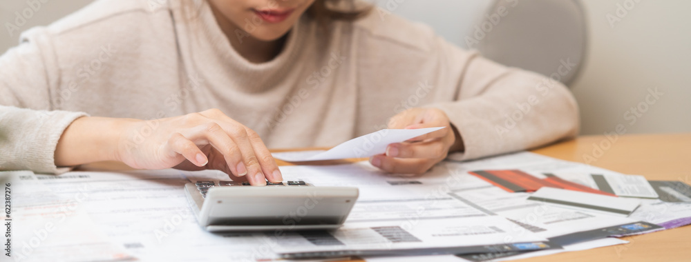 Fototapeta premium Financial owe asian young woman, girl suffer, stressed and confused, hand use calculator calculate expense from invoice or bill, have no money to pay, mortgage or loan. Debt, bankruptcy or bankruptcy.