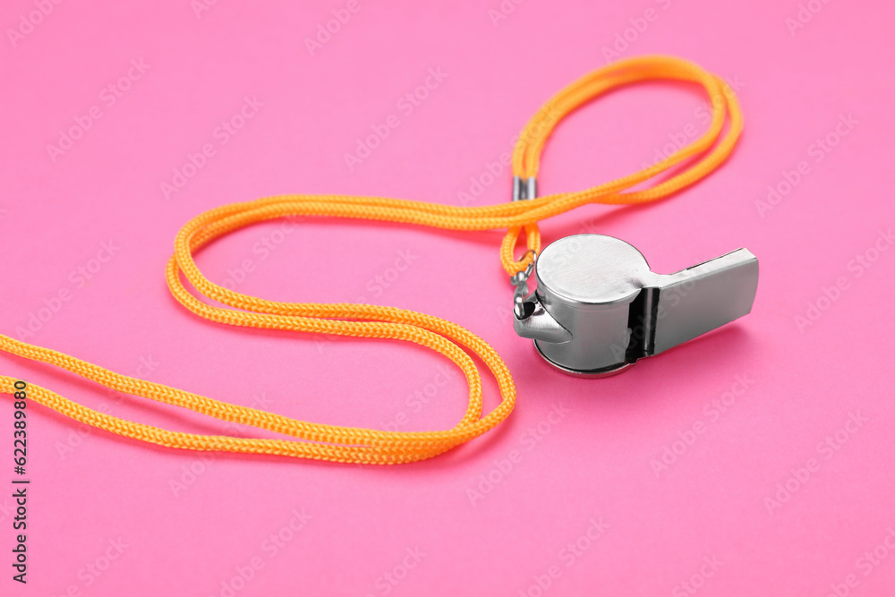 One metal whistle with cord on pink background One metal whistle with cord on pink background