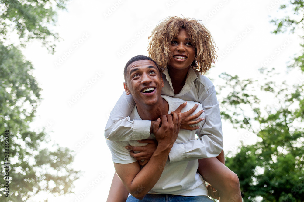 Fototapeta premium african american young couple in love runs together in the park in summer and smiles