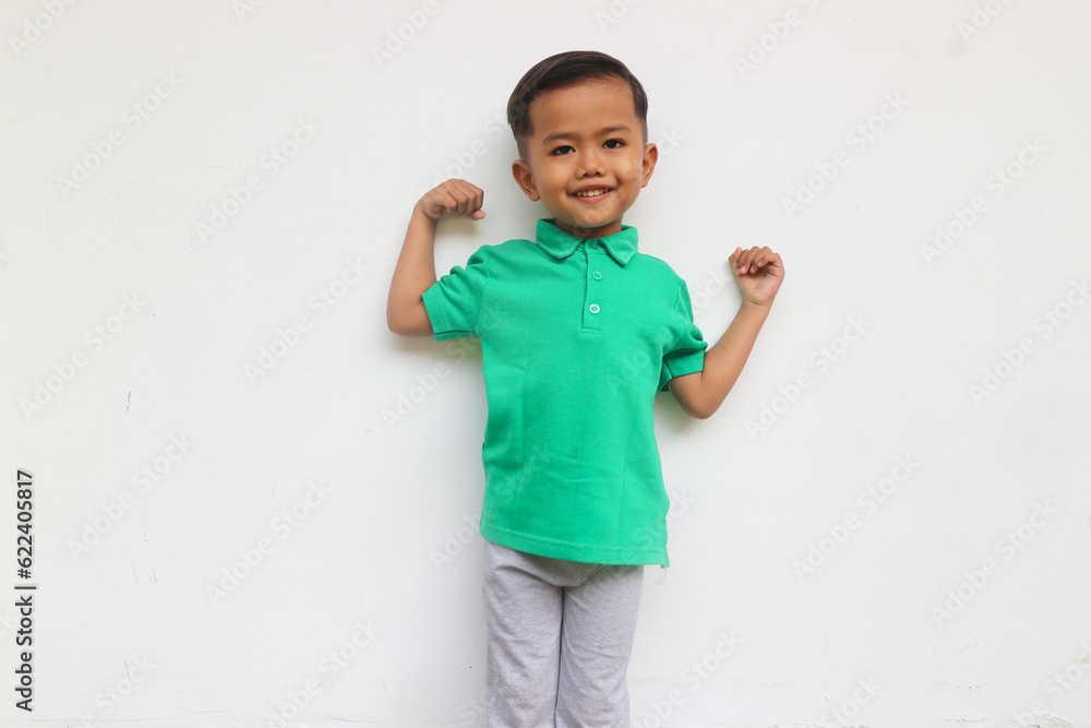 A smiling and confidence toddler boy looks at the camera raising his hands isolated on white background A smiling and confidence toddler boy looks at the camera raising his hands isolated on white background