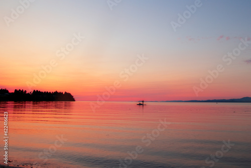 Ocean beach in sunrise and silhouette of a man on paddle boat. © Saeedatun