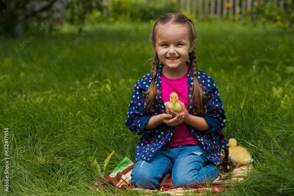 Little girl holding small ducklings in the garden. Close-up. Yellow duckling in her hands. Little girl holding small ducklings in the garden. Close-up. Yellow duckling in her hands.