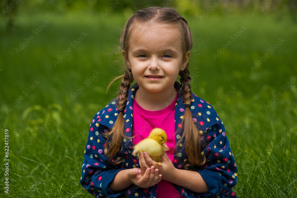 Little girl holding small duckling in the garden. Yellow duckling in her hands. Little girl holding small duckling in the garden. Yellow duckling in her hands.