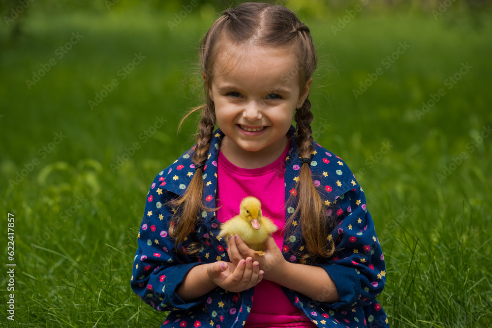 Little girl holding small duckling in the garden. Yellow duckling in her hands. Little girl holding small duckling in the garden. Yellow duckling in her hands.