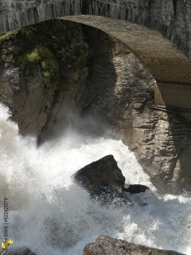 Photography Thundering river falls under stone bridge at the entrance to the Gasterntal, Swi