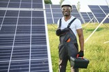 Portrait of african american electrician engineer in safety helmet and uniform installing solar panels.