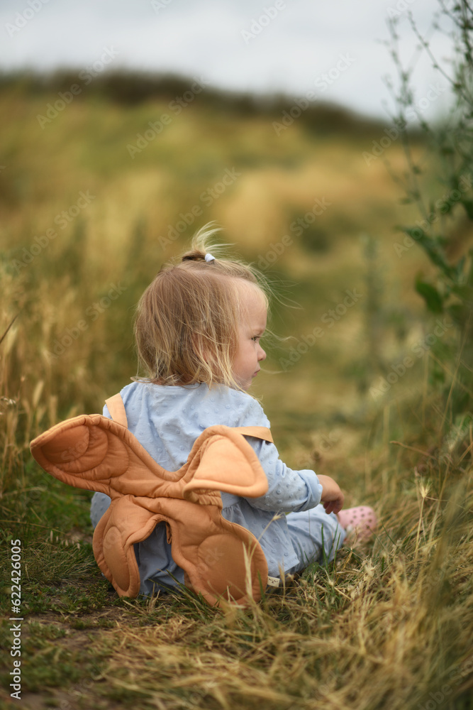 Little beautiful girl with backpack is walking in the field Little beautiful girl with backpack is walking in the field