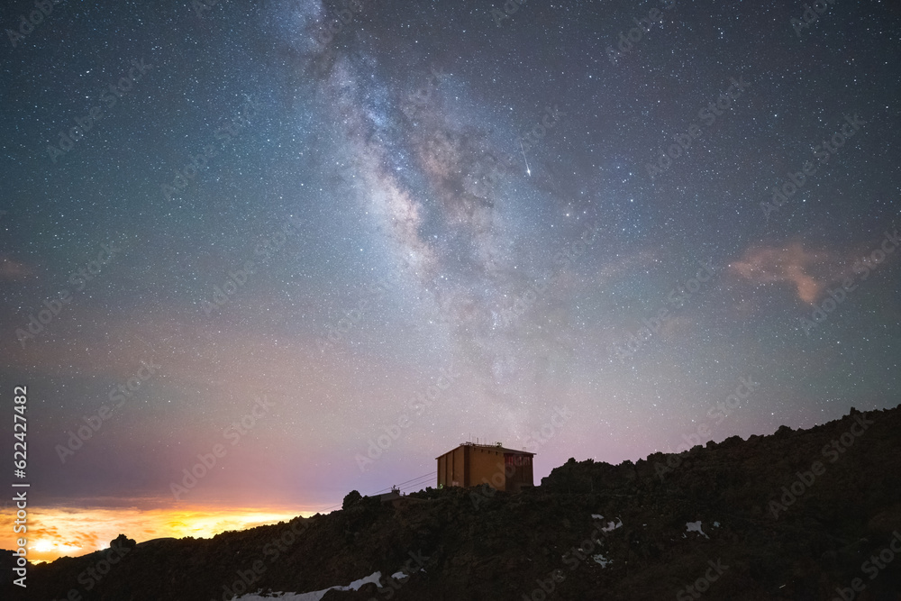 Amazing view of starry night with glowing stars and house on highland rocks Amazing view of starry night with glowing stars and house on highland rocks