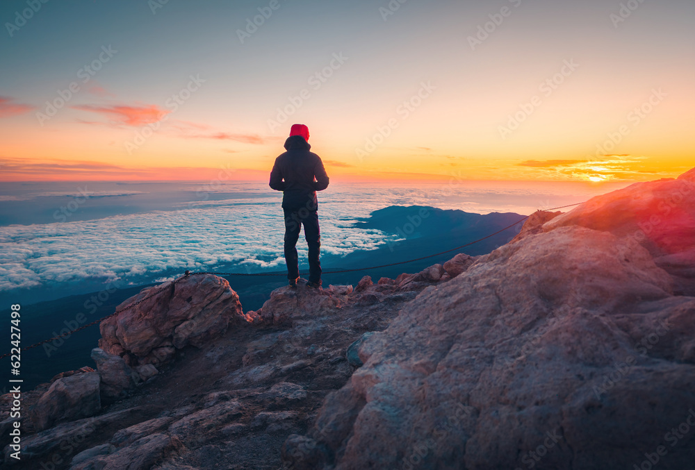 Unrecognizable traveller standing on highland and admiring sunset and sea Unrecognizable traveller standing on highland and admiring sunset and sea