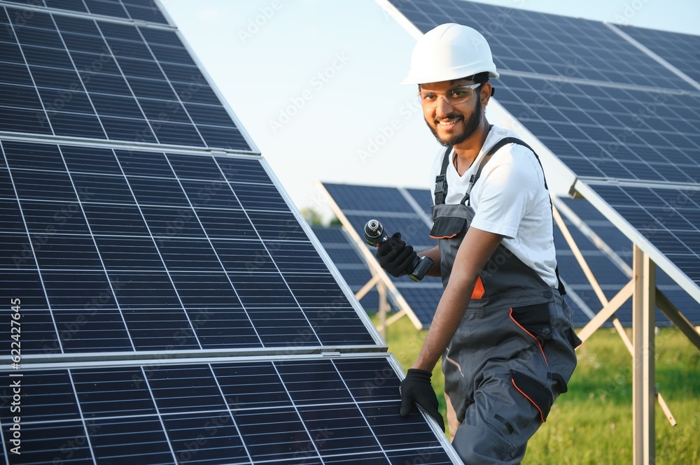 An Indian worker installs solar panels. The concept of renewable energy. An Indian worker installs solar panels. The concept of renewable energy.