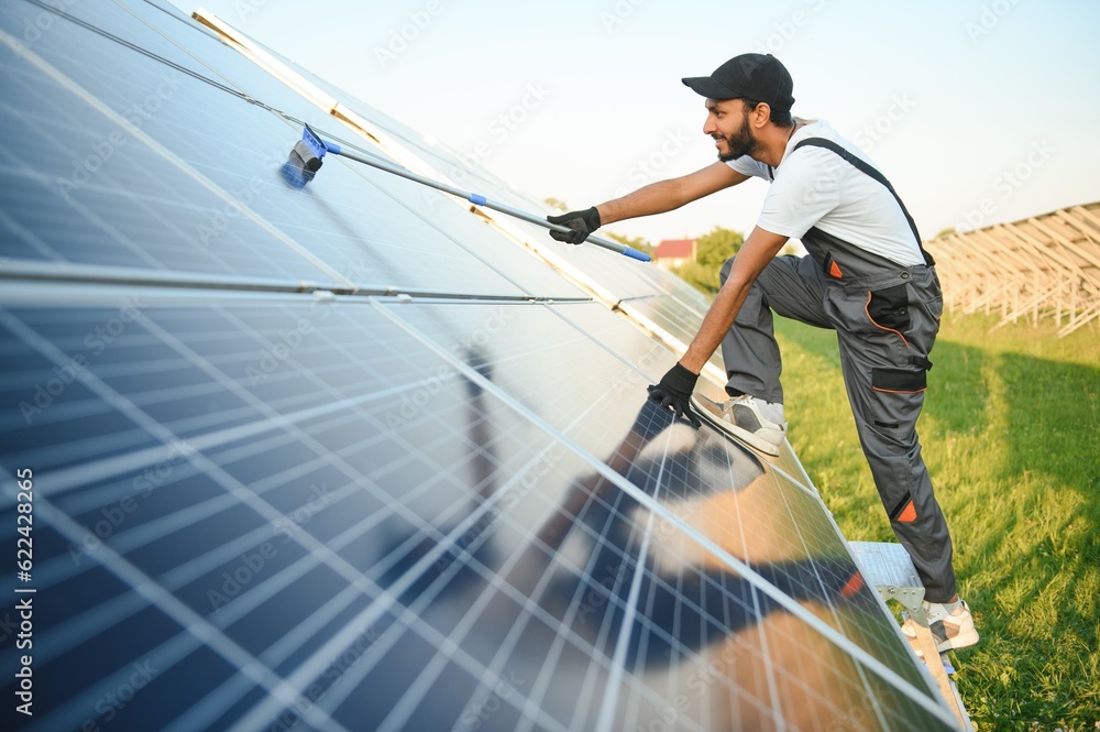 Indian handyman cleaning solar panels form dust and dirt. Indian handyman cleaning solar panels form dust and dirt.