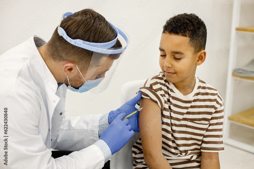 Fototapeta premium Male doctor doing a vaccination to a multiracional boy
