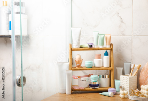 Care cosmetics on the shelf in the bathroom. Cosmetic tube. Cleanser, face and body cream, face roller and gua sha, tonic. Shelf with cosmetics in the interior of the bathroom.Beauty concept. 