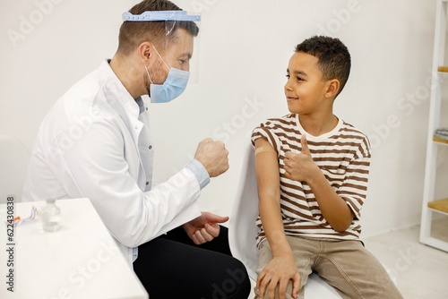 Male doctor stick a band-aid to a boy after a vaccination