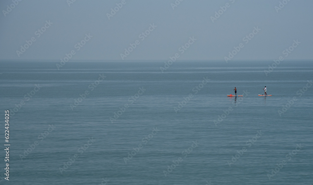 Unrecognized people canoeing in the sea in the morning. People exercising in the ocean