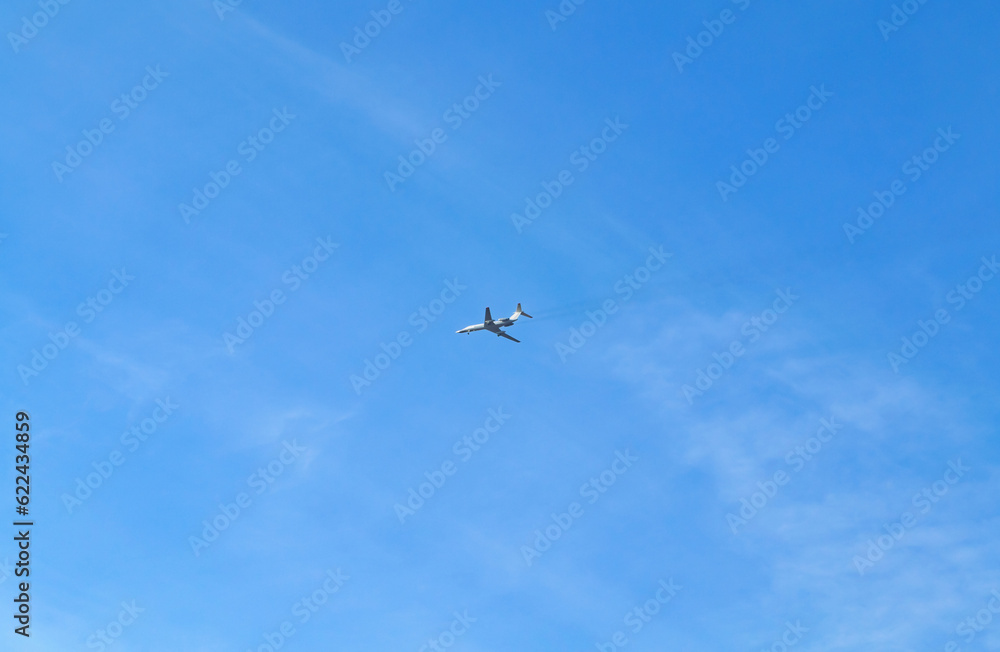 The plane flies high in the blue sky with small clouds The plane flies high in the blue sky with small clouds