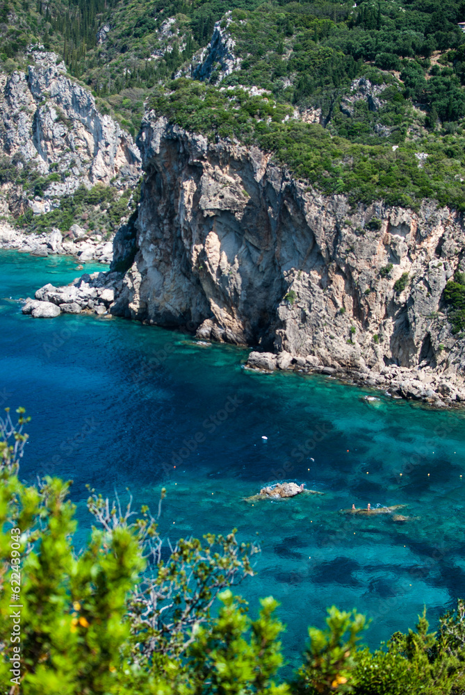 View of calm turquoise sea water and rocks. Pattern of sea surface and rocky shore. Ionian Sea, Greece. Rocky coast of the island Corfu, Paleokastritsa.