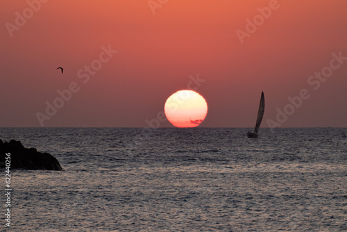 sequence of a sunset on Isla El Alacrán, Arica City, northern Chile, with a sailboat on the right side photo