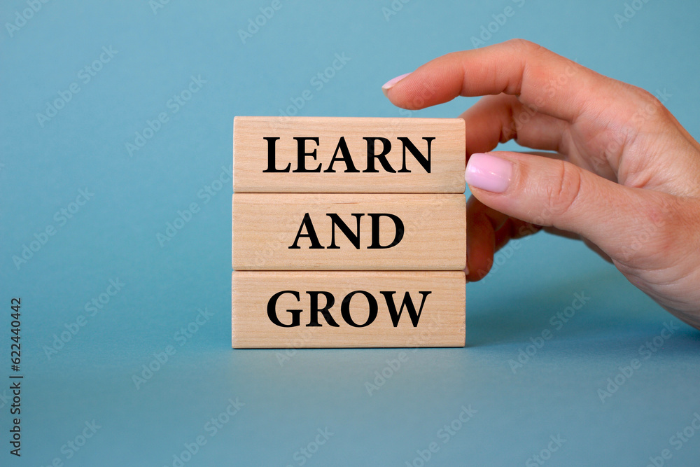 Learn and grow symbol. Wooden blocks with words Learn and grow. Business man hand. Beautiful blue background. Business and Learn and grow concept. Copy space. Learn and grow symbol. Wooden blocks with words Learn and grow. Business man hand. Beautiful blue background. Business and Learn and grow concept. Copy space.