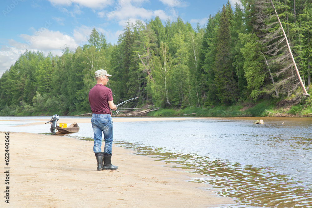 A man is fishing on the river on a summer day.Beautiful summer landscape on the river.