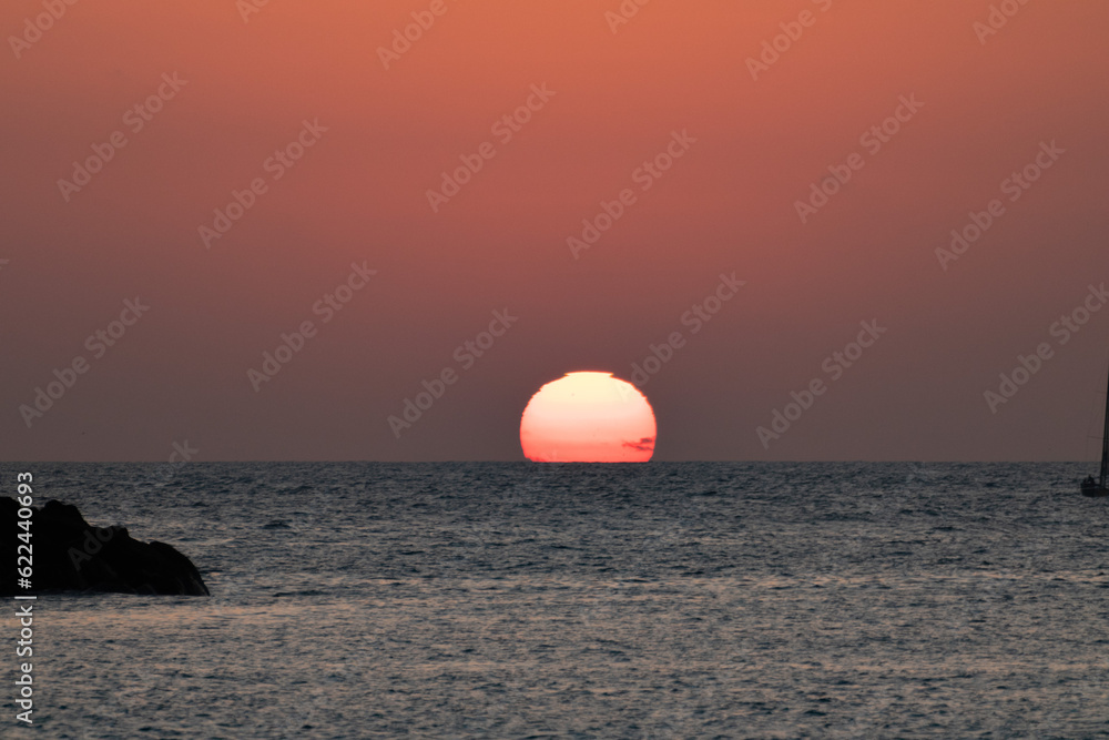 sequence of a sunset on Isla El Alacrán, Arica City, northern Chile, with a sailboat on the right side