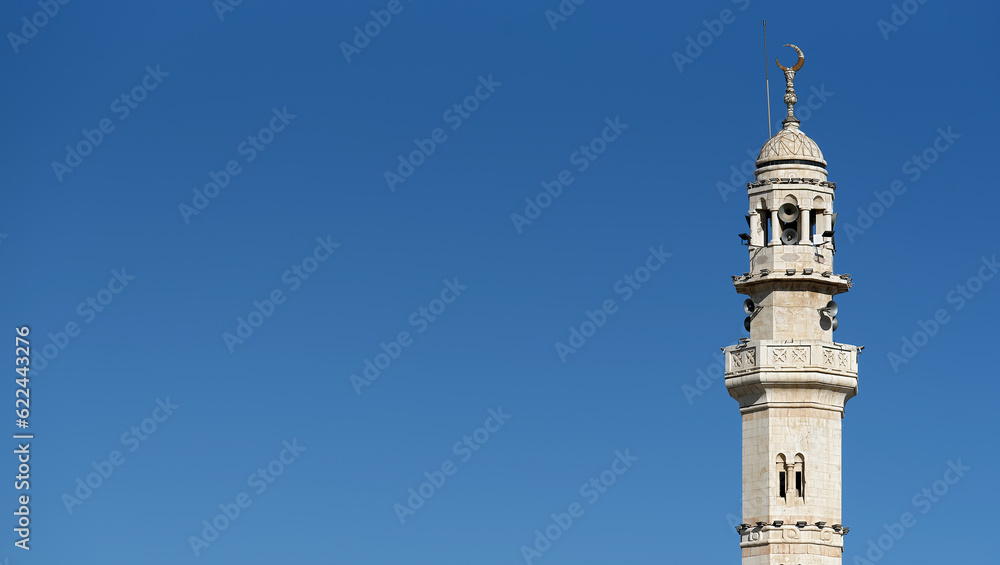 A mosque minaret against clear blue sky with copy space on left side
