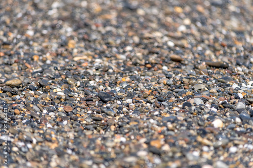 Colored pebbles on the beach of Greece with the waves of the sea covering them during a sunny day. Colored pebbles on the beach of Greece with the waves of the sea covering them during a sunny day.