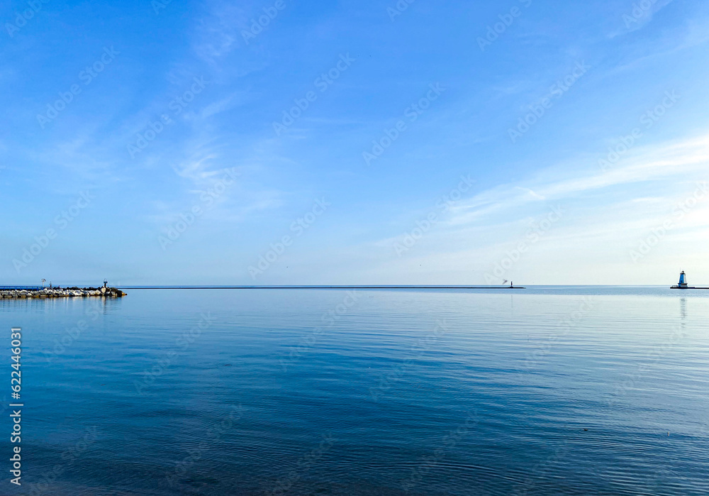 Calm blue waters of northern Lake Michigan with a cove and lighthouse in the disntance Calm blue waters of northern Lake Michigan with a cove and lighthouse in the disntance