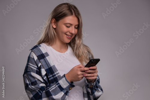 Surprised young woman isolated over gray background using mobile phone