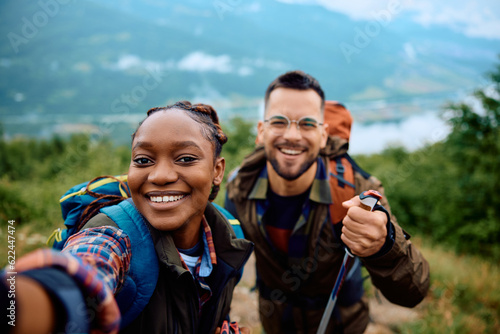 Foto Happy couple of hikers taking selfie on top of hill.
