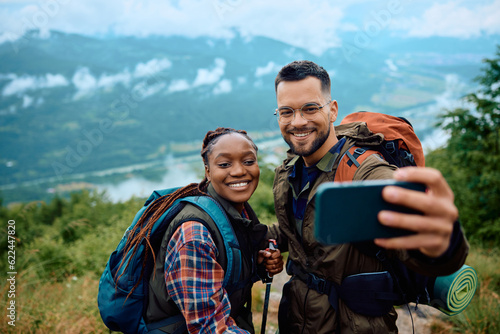 Foto Happy multiracial couple taking selfie while hiking in nature.
