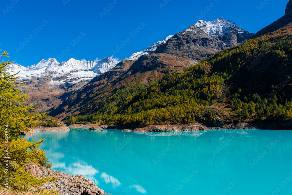 Autumnal landscape of the Lake Place Moulin, an artificial glacial lake with turquoise water in the italian Alps,  on the border with Switzerland