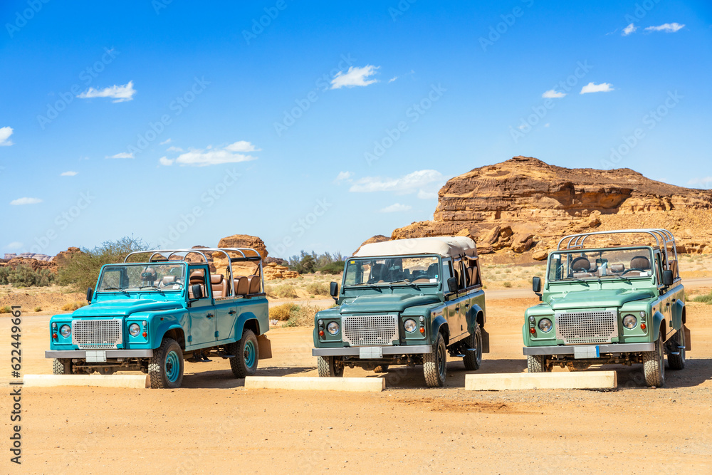 Off-road cars and desert cliffs formations landscape at Hegra, Al Ula, Saudi Arabia