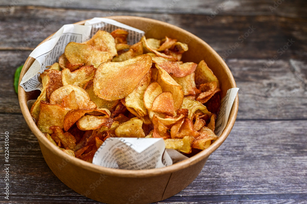 Delicious home made potato chips with sea salt and black pepper against a rustic background. Delicious snack served with sauce. Fast food.Beer snacks Delicious home made potato chips with sea salt and black pepper against a rustic background. Delicious snack served with sauce. Fast food.Beer snacks